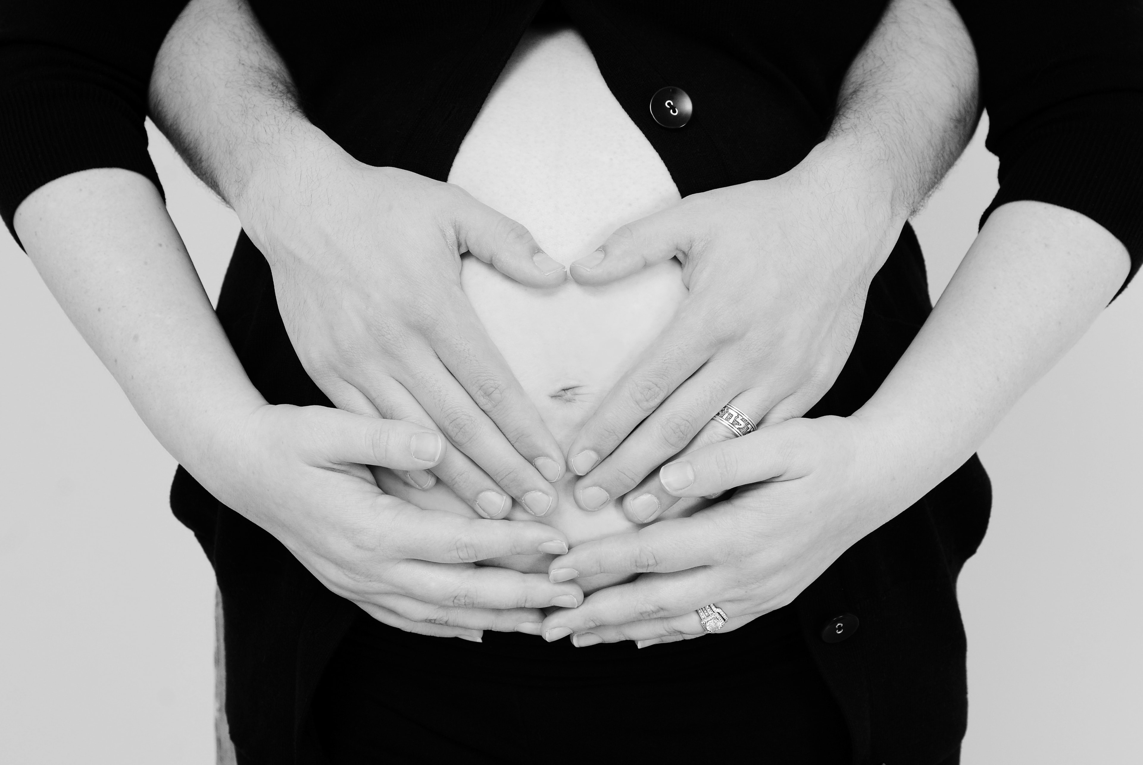 Couple hands forming heart over pregnant belly