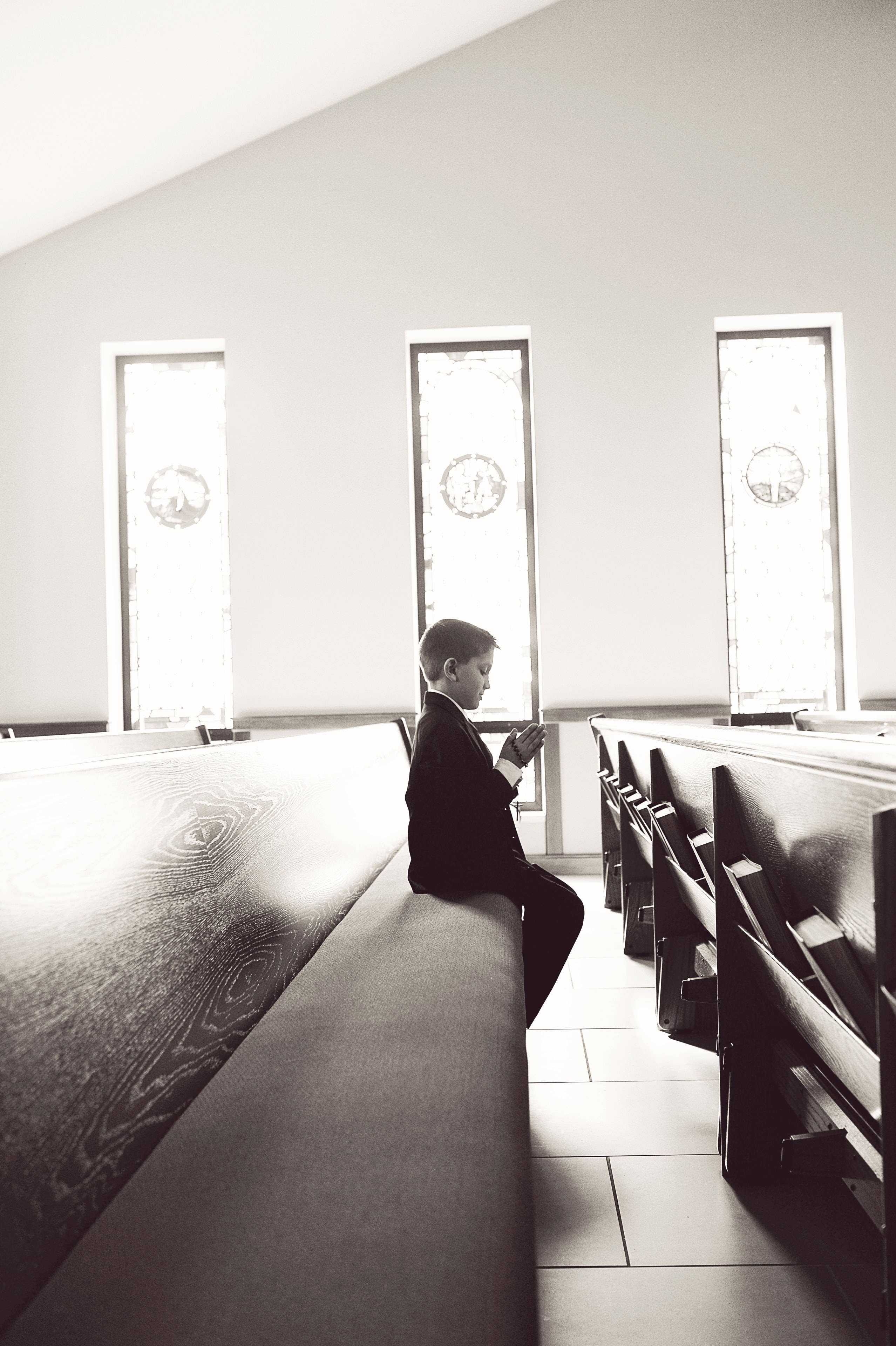 Boy praying alone in church pew