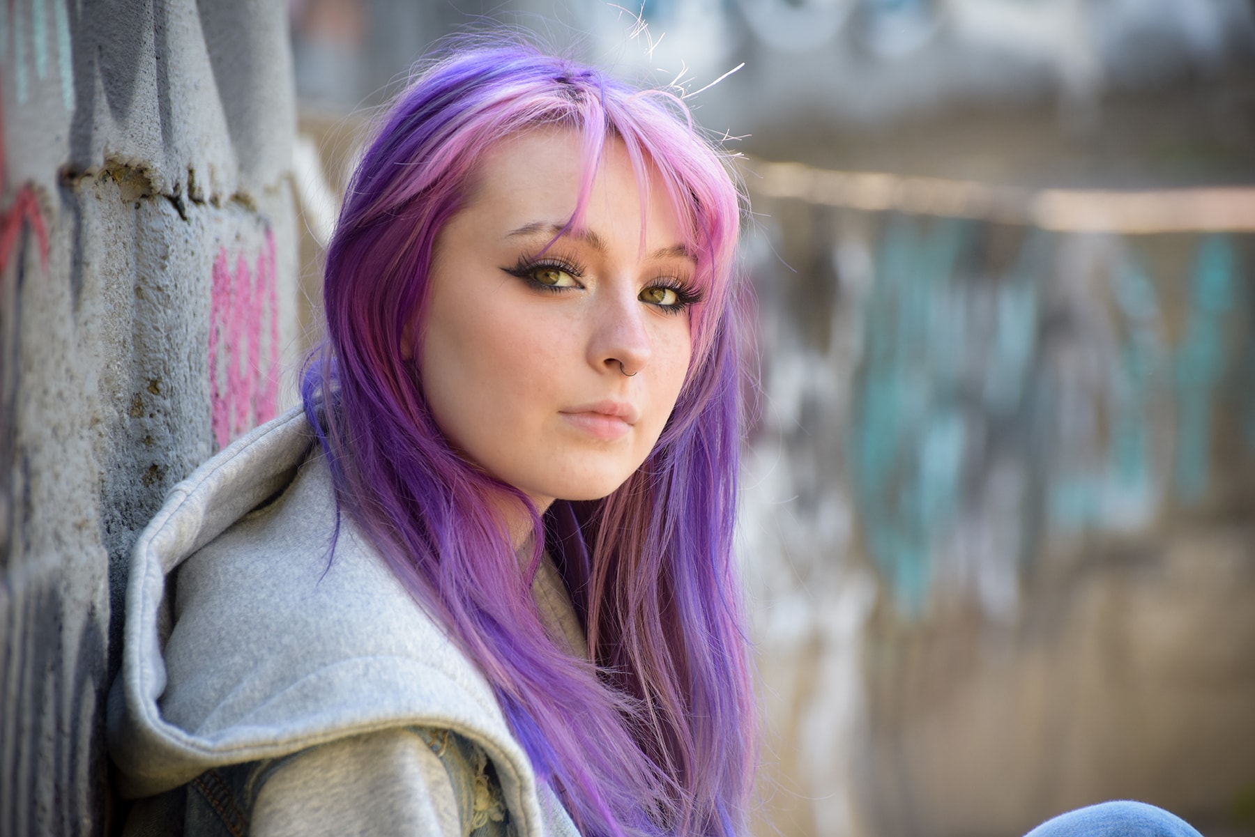 Woman with purple hair against graffiti wall